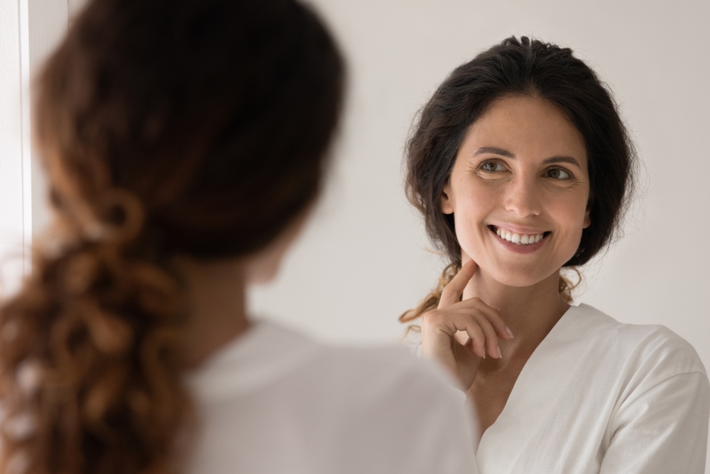 Woman looking in the mirror after Renaface® in Alpharetta, GA