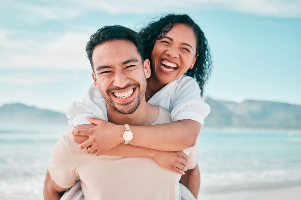 Man and woman laughing on a beach after treatment at BodyWorks in Alpharetta